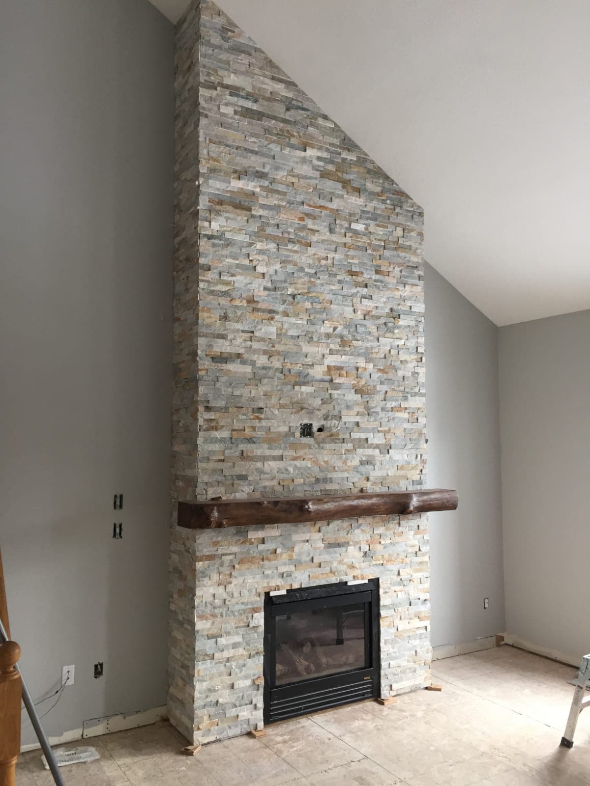 Living room fireplace with stacked-stone surround and wood mantel
